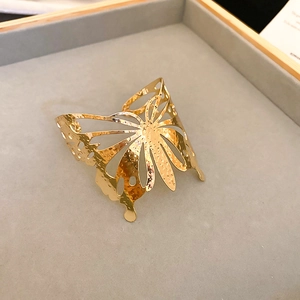 Primer plano del brazalete de mariposa dorada calada con textura de metal martillado