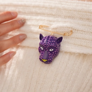 Vue macro détaillée d'une broche tête de léopard violette à pois roses sur tricot blanc