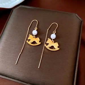 Golden rocking horse drop earrings with white pearls and hammer texture on chain