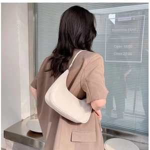Lifestyle shot of an off-white half-moon shoulder bag worn by a model in a shop setting