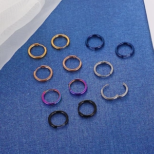 Set of minimalist stainless steel hoop earrings in six metallic colors on blue texture