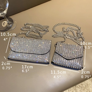 Silver rhinestone evening clutch bags with chain straps in two sizes on a grey surface