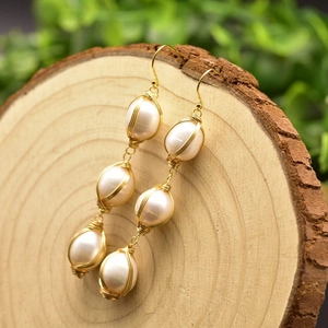 Detail of baroque pearl drop earrings with hand-wrapped gold wire in a birdcage nest design