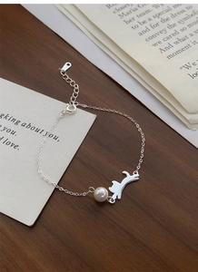 Dettaglio del bracciale in argento S925 con ciondolo a gatto e perla su fondo in legno