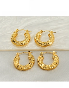 Macro shot of gold-plated titanium steel earrings with a hammered lava texture finish