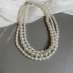 Elegant three-layer pearl necklace with silver clasp on white silk background