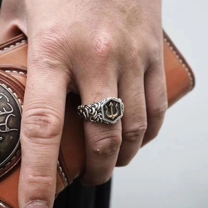 Vintage silver trident ring for men with golden sea god emblem on leather background