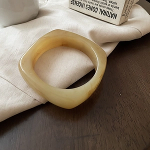 Detail view of amber resin bangle with marble texture on minimalist linen background