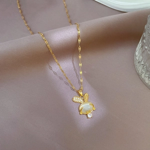 Macro shot of gold rabbit necklace with white opal and zircon on silk backdrop