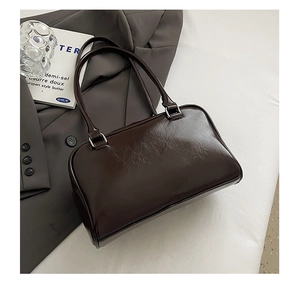 Detail of dark brown glossy patent leather bowling bag on aesthetic still life backdrop