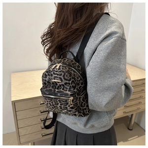 Side view of a trendy leopard print mini backpack with gold zippers worn by a model