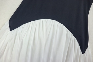 Detailed view of the black and white patchwork design and pleated hem on this A-line dress