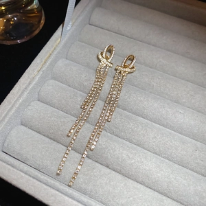 Detail view of long tassel earrings with sparkling white micro-diamonds in a gold finish