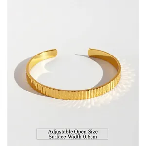 Minimalist gold ribbed cuff bracelet featuring a textured vertical pattern and open design