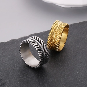 Macro shot of silver and gold feather rings showing textured carving on black stone