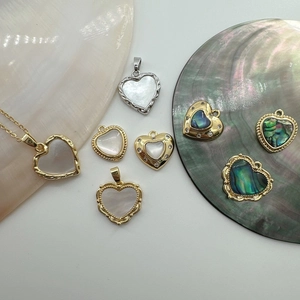 Detailed view of heart-shaped shell pendants with gold plating and abalone textures