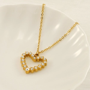 Elegant gold heart pendant necklace with shimmering crystals on a decorative ceramic tray