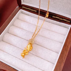 Golden koi fish pendant necklace with sparkling zircon on a brown wooden jewelry box
