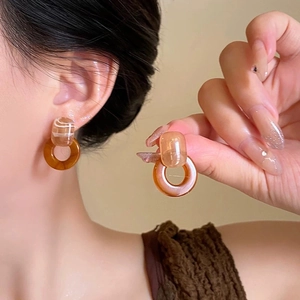Detail of amber acrylic resin earrings with geometric design shown on a female model