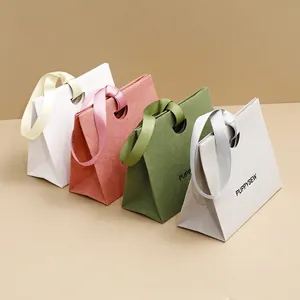 Minimalist trapezoid paper gift bags with satin ribbon handles in four soft colors