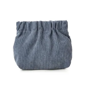 Blue corduroy mini cosmetic bag with squeeze top closure and vertical stripe texture