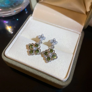 Macro view of four-leaf clover earrings with green crystals and pearl details