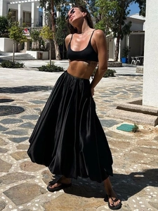 Elegant high-waisted black A-line midi skirt with subtle satin finish in outdoor lighting
