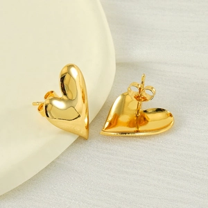 Chic 18K gold plated stainless steel 3D heart stud earrings on a ceramic dish