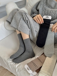 Close-up of ribbed knit cotton socks in various warm colors displayed on a beige sofa