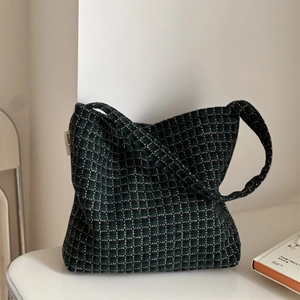 Macro detail of dark green plaid wool fabric texture and white simple label on tote bag