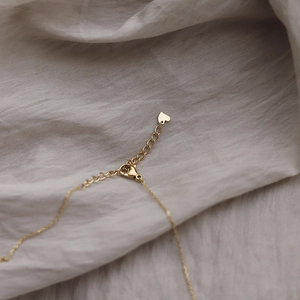 Détail du fermoir mousqueton et du pendentif cœur sur collier en titane doré