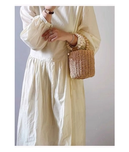 Close-up of a woven bucket bag with beaded handle paired with a white dress
