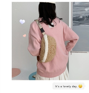Detail of cute beige faux shearling waist bag with minimalist bear embroidery and strap