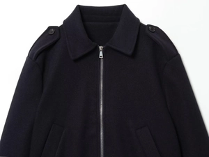 Détail du col à revers avec fermeture éclair métallique et épaulettes sur veste en laine