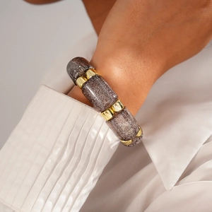 Close-up of geometric acrylic bead bracelet with golden spacers on a wrist