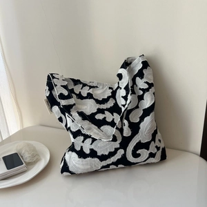 Close-up of black and white paisley embroidery texture on a minimalist cotton linen bag
