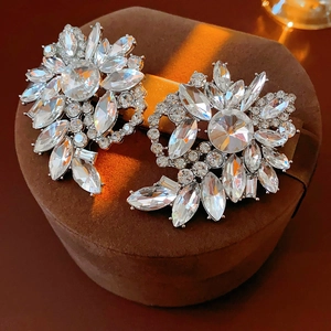 Close-up of sparkling heart-shaped earrings with rhinestones on a brown velvet box