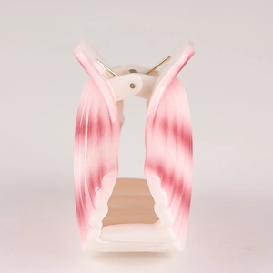 Detailed shot of pink and white shell-patterned hair clip with shiny plastic finish