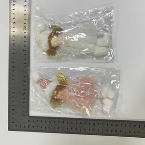Detailed view of plush angel dolls with sequin wings measured by a steel ruler