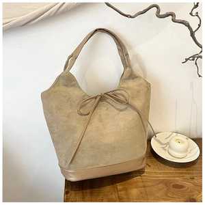 Detail of khaki suede tote bag showing material texture and leather bow decoration