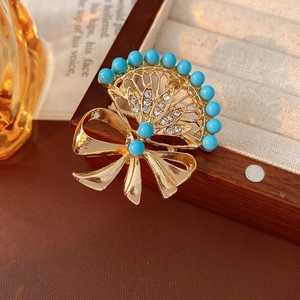 Detail of vintage fan-shaped brooch with blue beads and bowknot on velvet box