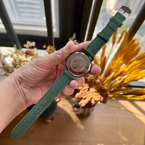 Detail view of water resistant quartz watch with green suede strap and stainless steel back