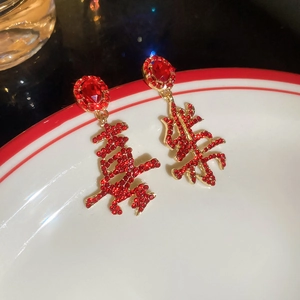 Detail view of Chinese Xi character red earrings with rhinestones on a ceramic plate