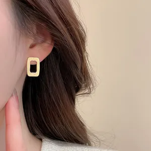 Close-up of golden hollow rectangular earrings with elegant brushed metal texture