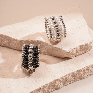 Detail of multi-row beaded rings with faux pearls and silver beads on stone