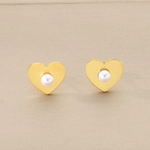Gros plan sur des boucles d'oreilles cœur en or avec perles blanches centrales et métal poli