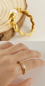 Detail of 18k gold spiral ring with white pearl on wood and worn on finger