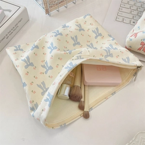 Detailed view of floral canvas makeup bag with blue bow pattern and metal zipper closure