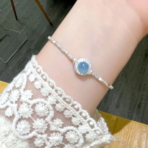 Close-up of a silver bracelet with a round light blue gemstone on a woman's wrist