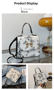 Detail of white butterfly print handbag with golden bow metal clasp and black handle